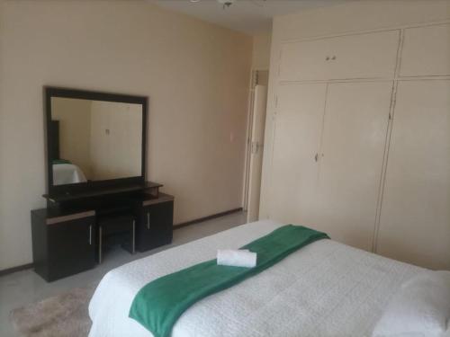 1 dormitorio con cama y espejo grande en Spacious Executive Holiday Apartment In Bulawayo en Bulawayo