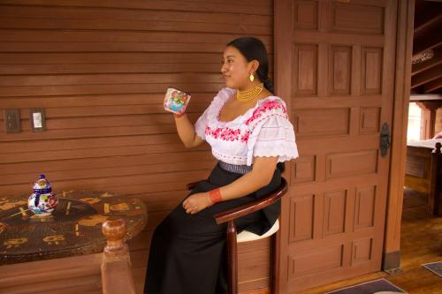 una mujer sentada en una silla sosteniendo un pedazo de comida en Chaska Hotel, en Otavalo
