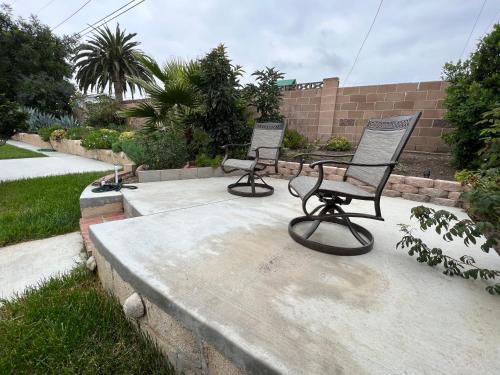 two empty chairs sitting on a concrete patio at Modern 3 King Beds, Beautiful Large Backyard, WFH, Long Stays, Waterfall, WI-FI, FWY, 25 mins to Beach in Thousand Oaks