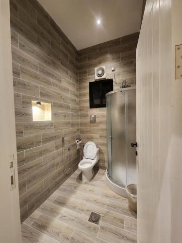 a bathroom with a toilet and a tv on the wall at شاليه ومنتجع النخيل الريفي بالطائف in As Sayl aş Şaghīr