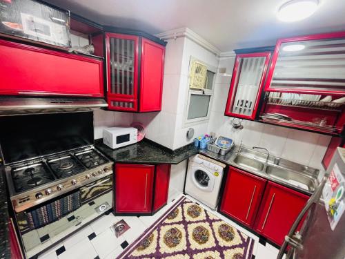 a kitchen with red cabinets and a stove and a sink at Fourth star in Alexandria