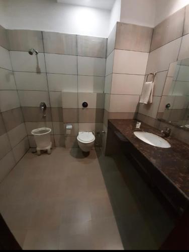 a bathroom with two sinks and a toilet and a mirror at The mirage in Ludhiana