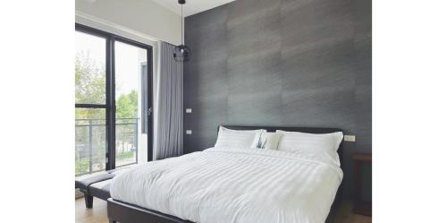 a bedroom with a white bed with a large window at Dear house Homestay in Puli