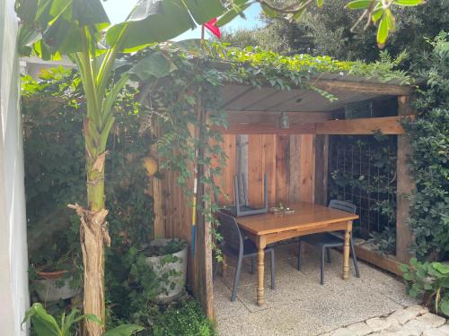 une table en bois sous une pergola dans un jardin dans l'établissement MAISON indépendante avec Jardin, très calme, CENTRE VILLE LA ROCHELLE, à La Rochelle