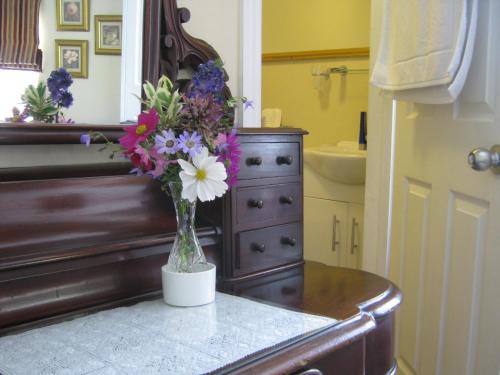 a vase of flowers on top of a dresser at Holly Tree B&B in Bromyard