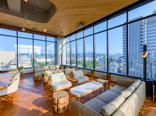 a living room with couches and chairs and large windows at THE KNOT HIROSHIMA in Hiroshima