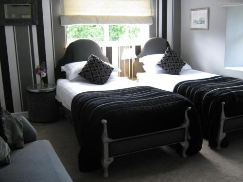 two beds in a room with a window at Holly Tree B&B in Bromyard