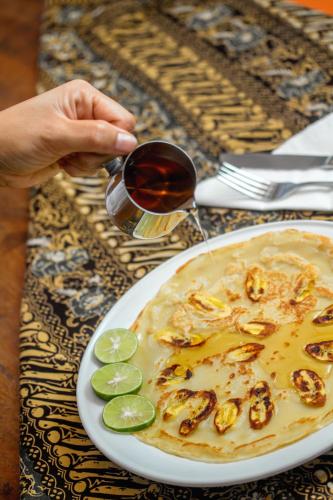 a person holding a glass of wine next to a plate of food at Bamboo Paradise in Padangbai