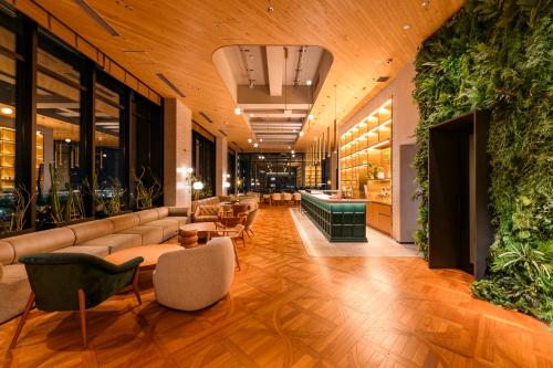 a lobby with couches and tables and plants at THE KNOT HIROSHIMA in Hiroshima