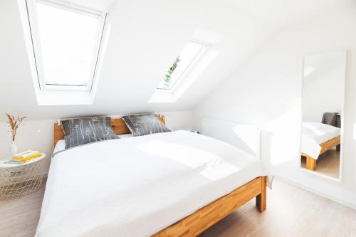 a white bedroom with a bed and two windows at Casa Ueberall in Fehmarn