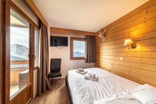 1 dormitorio con 1 cama, 1 silla y 1 ventana en Le Croc Blanc en Morzine