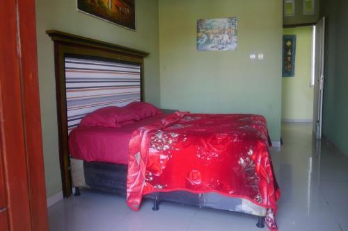 Un dormitorio con una cama con una manta roja. en OYO Life 90646 Villa Karsinem Pasuruan en Pasuruan