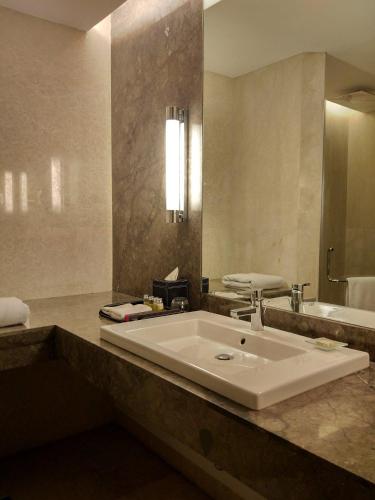 a bathroom with a large sink and a bath tub at The Anya Hotel-Golf Course Road in Gurgaon