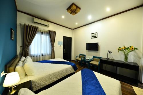 a hotel room with two beds and a desk at Hanoi Starlight Boutique Hotel in Hanoi