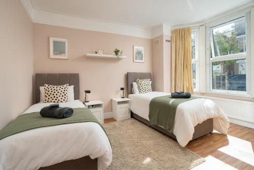 sypialnia z 2 łóżkami i oknem w obiekcie Homely and Stylish Apartment with a garden in East Finchley w Londynie