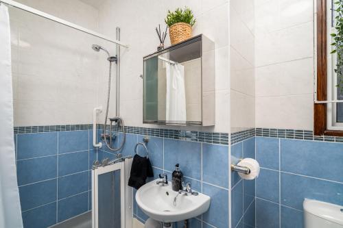 ein blau-weißes Bad mit einem Waschbecken und einer Dusche in der Unterkunft Homely and Stylish Apartment with a garden in East Finchley in London