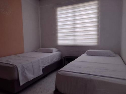 two beds in a small room with a window at Buganviles 16, !Pura Vida! in Girardot