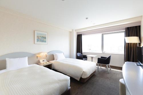 a hotel room with two beds and a desk at Kawagoe Prince Hotel in Kawagoe