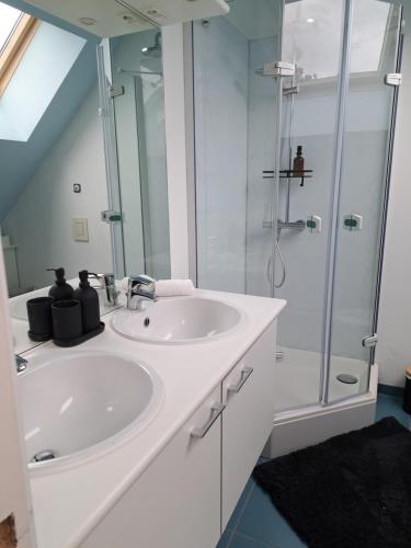 La salle de bains blanche est pourvue d'un lavabo et d'une douche. dans l'établissement Chambres d'hôtes et kots à 2h de Paris jeux olympiques, à Lens