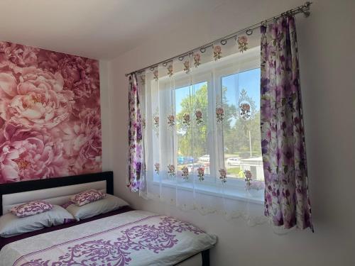 トレボンにあるApartmán na Lukách - Kopretinaのベッドルーム1室(ピンクの花のカーテン付きの窓付)