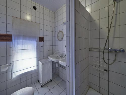 een wit betegelde badkamer met een wastafel en een douche bij Lovely Apartment in Mesch with Parking in Mesch