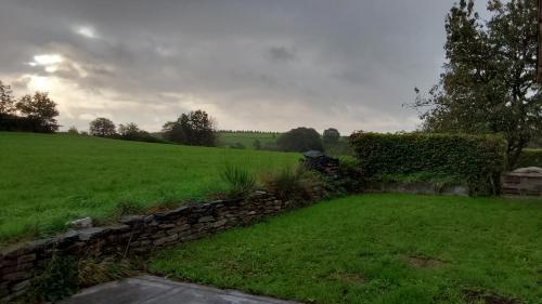 een tuin met een stenen muur en een groen veld bij La clef des champs in Houffalize