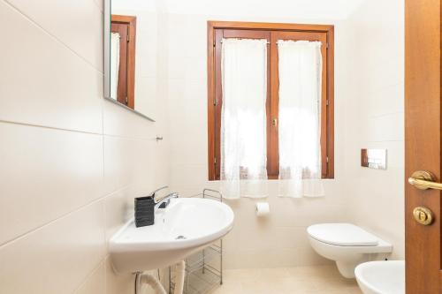 a white bathroom with a sink and a toilet at Hotel L'Ulivo in Girasole