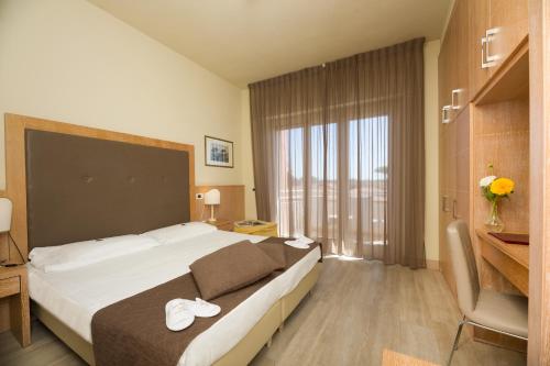 Cette chambre comprend un grand lit et une grande fenêtre. dans l'établissement Hotel Nuova Sabrina, à Marina di Pietrasanta