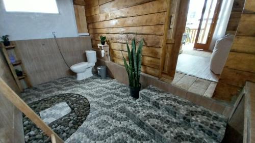 a bathroom with a toilet and a plant in the floor at Raturinjani homestay in Selong