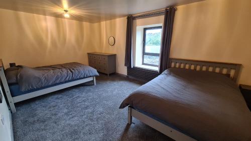 1 dormitorio con 2 camas y ventana en Barn near Colne for Leisure or Business en Colne