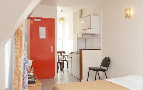 a red door in a small room with a kitchen at Hotel Ferney République in Paris