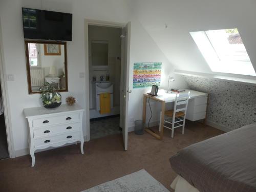 une chambre avec un lit, un bureau et un miroir dans l'établissement Le clos fleuri - Chambres d'hôtes, à Onzain