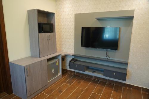 a room with a flat screen tv and a entertainment center at Mevid Hotels in Hyderabad