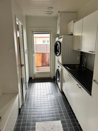 a kitchen with white cabinets and a black tile floor at Guest house - Northern tealight in Rovaniemi