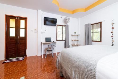 ein weißes Schlafzimmer mit einem Bett und einem Schreibtisch in der Unterkunft Garden Home 3 in Haad Yao
