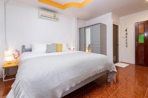 ein weißes Schlafzimmer mit einem weißen Bett und einem Holzboden in der Unterkunft Garden Home 3 in Haad Yao
