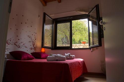 1 dormitorio con cama roja y ventana en La Terrazza di Cirico', en Carlentini