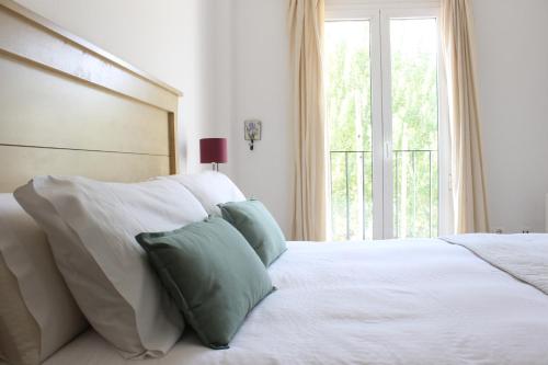 ein Schlafzimmer mit einem weißen Bett mit Kissen und einem Fenster in der Unterkunft Casa Rural La Senda de Aroche in Aracena