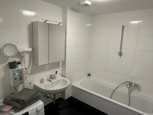 a white bathroom with a sink and a bath tub at Paky Appartements 00323 in Bruck an der Leitha