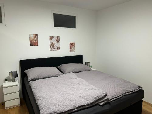een bed in een slaapkamer met een witte muur bij Paky Appartements 00323 in Bruck an der Leitha
