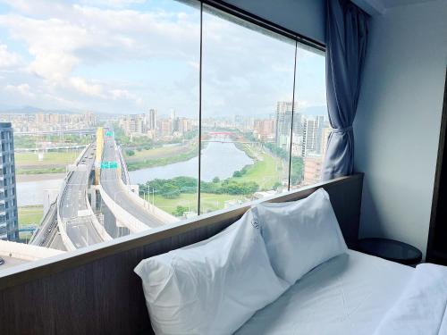 a bedroom with a large window with a view of a city at Hermit Dorm in Taipei
