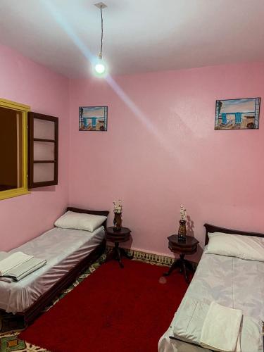2 łóżka w pokoju z różowymi ścianami w obiekcie Dar Diyafa w mieście El Ksiba