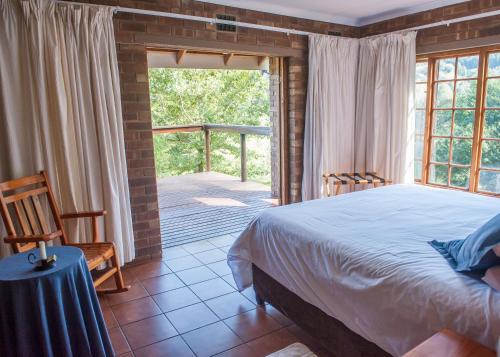 a bedroom with a bed and a large window at Cheerio Trout Fishing & Holiday Resort in Haenertsburg