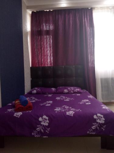 a purple bed with a purple comforter and a window at Gldani-house in Tbilisi City