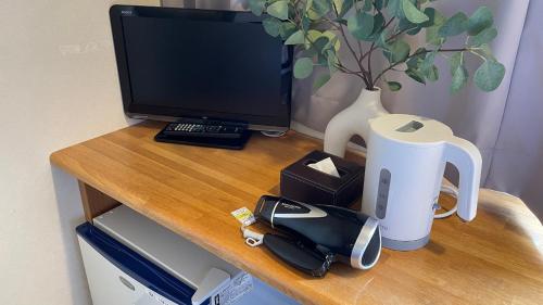 a desk with a computer monitor and a telephone on it at 米子シティガーデンズホテル Yonago Citygardens Hotel in Yonago