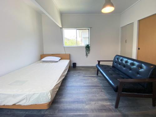 ein Zimmer mit einem Bett und einem Sofa darin in der Unterkunft カモゲストハウス in Tsuruoka