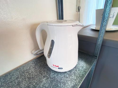 a white tea kettle sitting on a counter at カモゲストハウス ペット不可 in Tsuruoka