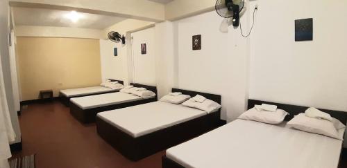 three beds in a room with white walls at Angel & Marie's Basic ACroom for 4-8pax in San Juan
