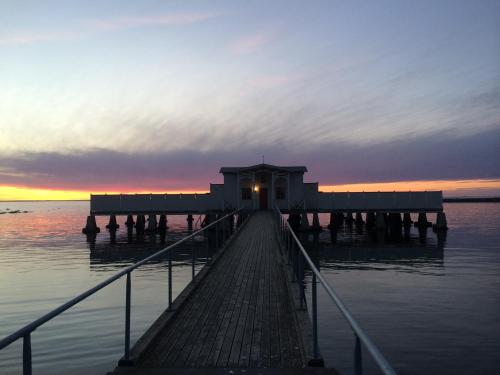 uma doca na água com um pôr-do-sol ao fundo em Borgholm Rum Centralt em Borgholm