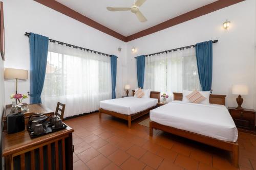 a hotel room with two beds and a television at Atoh's Maison in Siem Reap